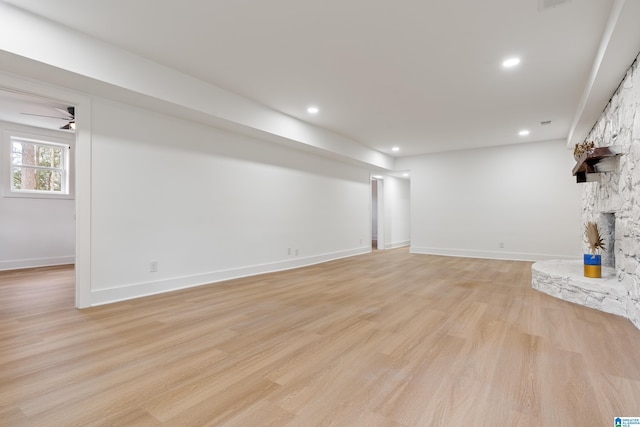 unfurnished living room with ceiling fan, a fireplace, and light hardwood / wood-style flooring