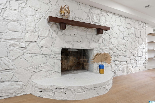 room details with a stone fireplace and wood-type flooring