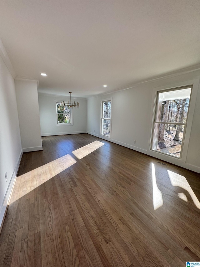 unfurnished room featuring crown molding, a notable chandelier, and dark hardwood / wood-style flooring