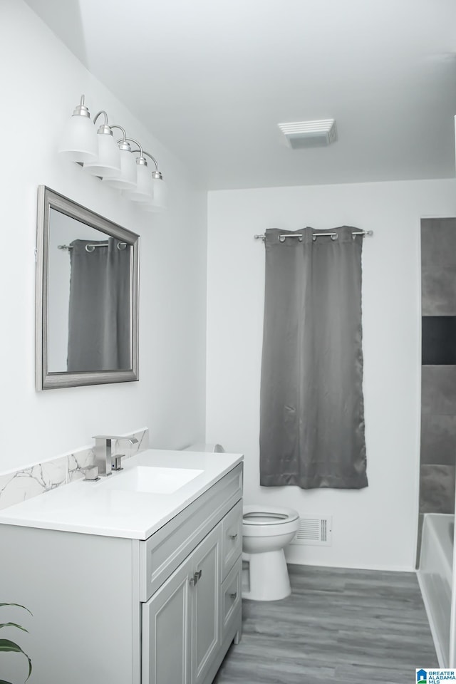 bathroom with vanity, toilet, and hardwood / wood-style floors