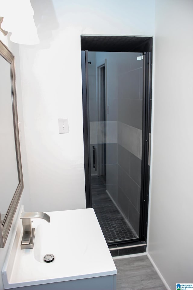 bathroom with walk in shower, vanity, and hardwood / wood-style floors