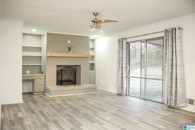 unfurnished living room with hardwood / wood-style flooring, a fireplace, ornamental molding, and built in shelves