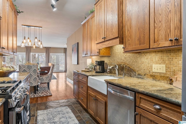 kitchen featuring sink, appliances with stainless steel finishes, light stone counters, tasteful backsplash, and decorative light fixtures