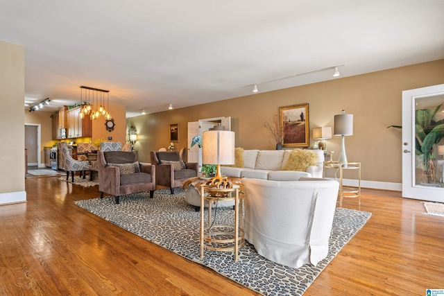 living room featuring an inviting chandelier, track lighting, and light hardwood / wood-style floors