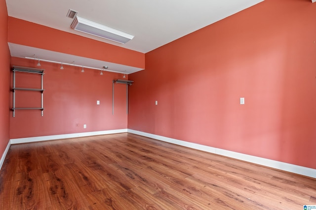 empty room with hardwood / wood-style flooring and rail lighting