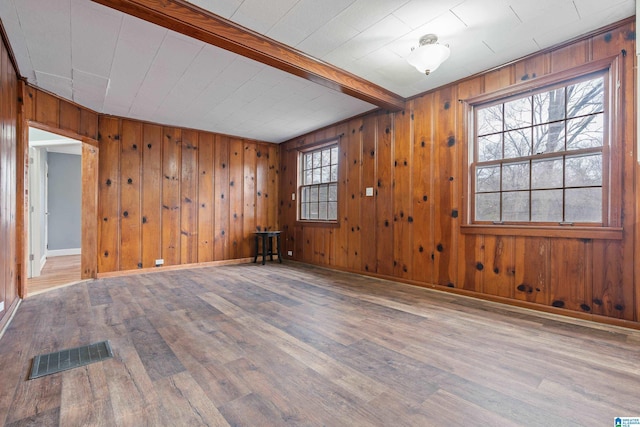 spare room featuring hardwood / wood-style flooring, wooden walls, and beamed ceiling