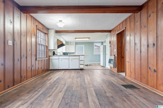 interior space with hardwood / wood-style floors, sink, heating unit, and beam ceiling