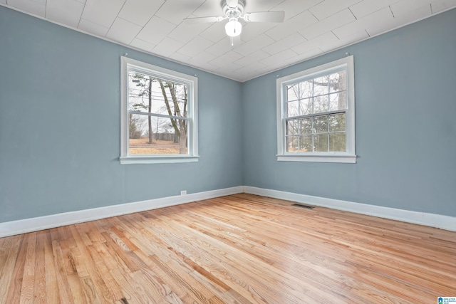 unfurnished room featuring a wealth of natural light, ceiling fan, and light wood-type flooring