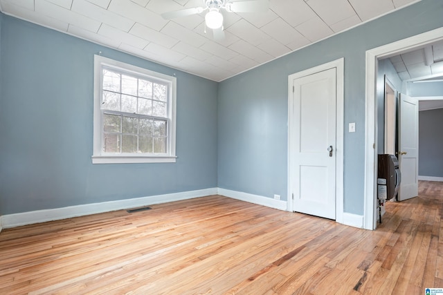 empty room with heating unit, ceiling fan, and light hardwood / wood-style flooring