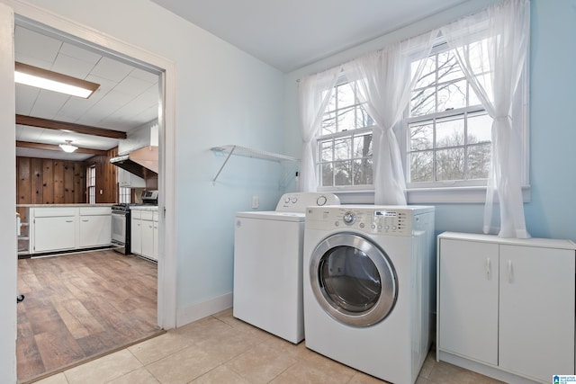 washroom featuring light tile patterned flooring, washing machine and clothes dryer, and wood walls