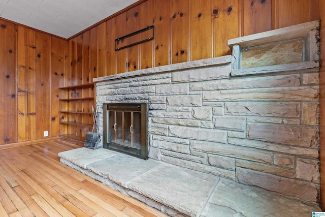 room details with hardwood / wood-style flooring, a fireplace, ornamental molding, and wooden walls