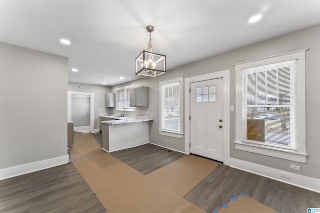 kitchen featuring pendant lighting, gray cabinetry, dark hardwood / wood-style floors, a healthy amount of sunlight, and kitchen peninsula