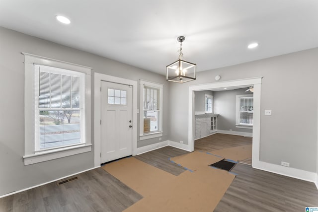 foyer entrance with an inviting chandelier and dark wood-type flooring