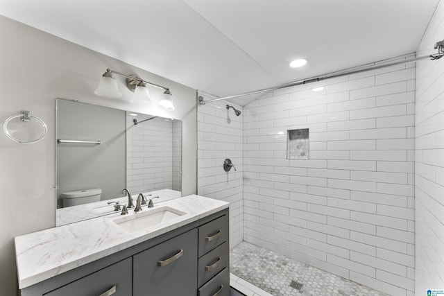 bathroom with tiled shower, vanity, and toilet