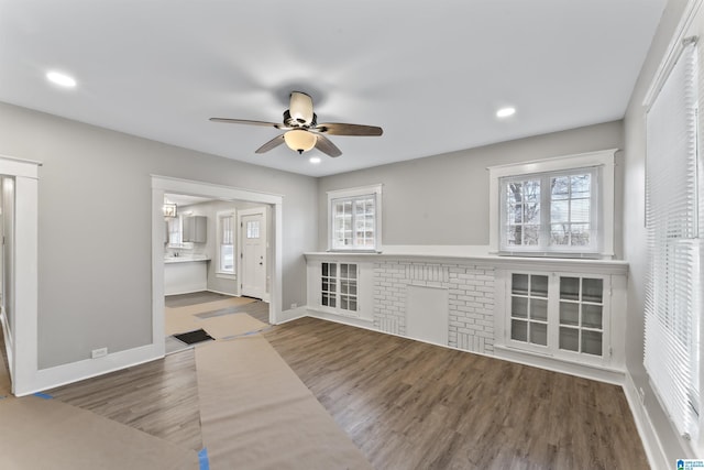 unfurnished living room with a wealth of natural light, wood-type flooring, and ceiling fan