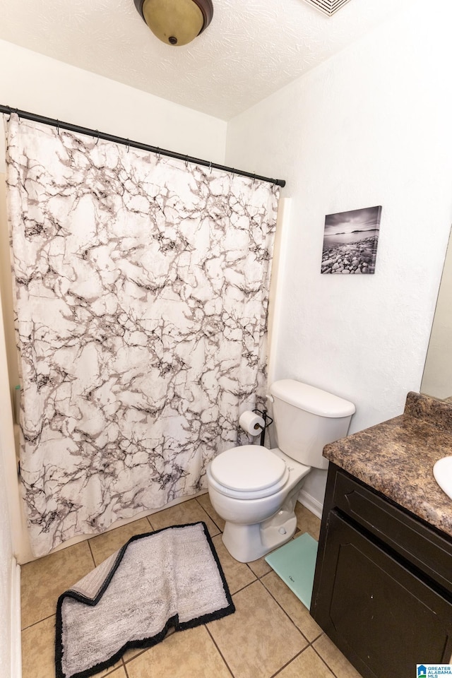 bathroom with tile patterned floors, toilet, a textured ceiling, and vanity