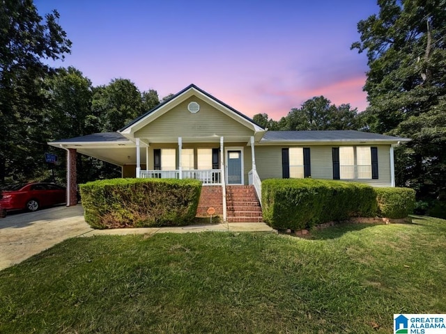 ranch-style home with a porch, a carport, and a lawn