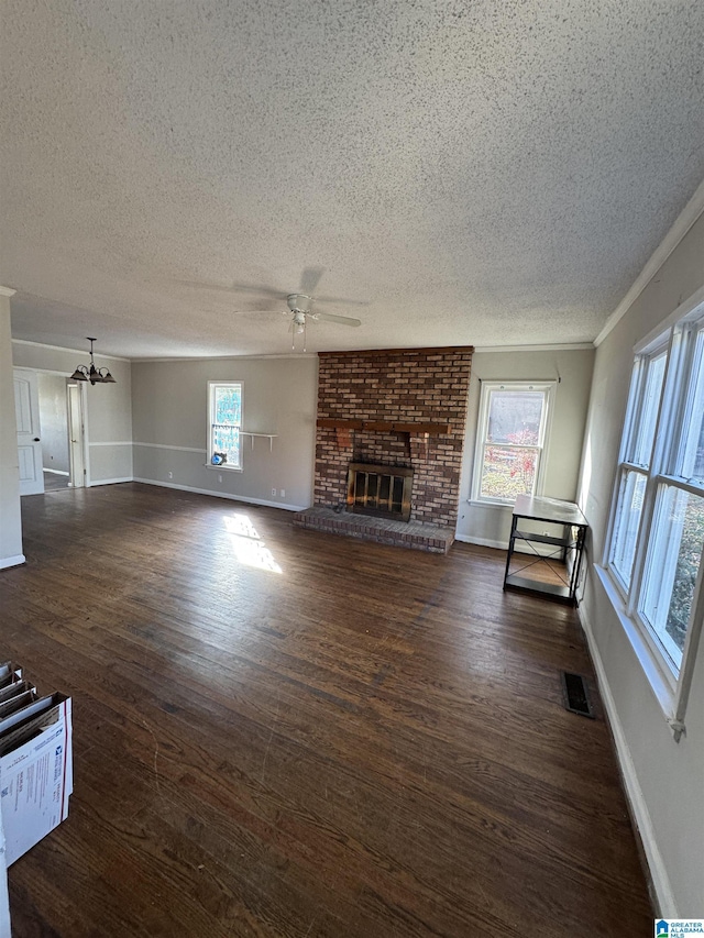 unfurnished living room featuring dark wood-type flooring, ceiling fan, a fireplace, and crown molding