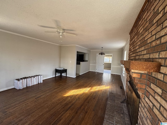 unfurnished living room featuring crown molding, a brick fireplace, a textured ceiling, dark hardwood / wood-style floors, and ceiling fan with notable chandelier