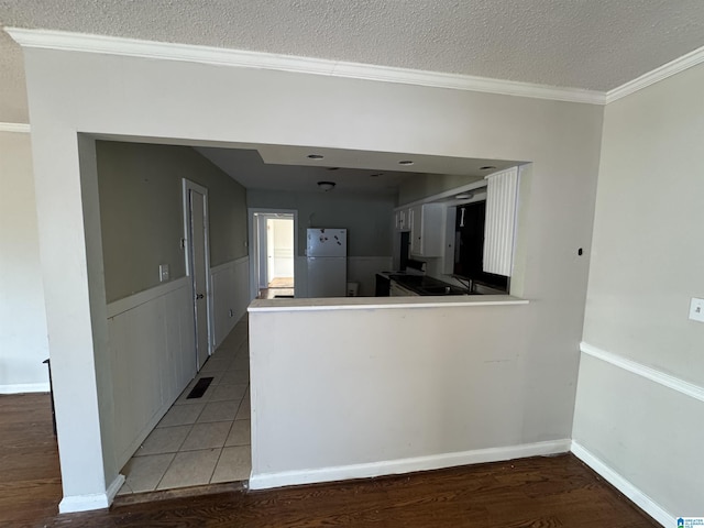 kitchen with sink, light hardwood / wood-style flooring, a textured ceiling, white refrigerator, and ornamental molding