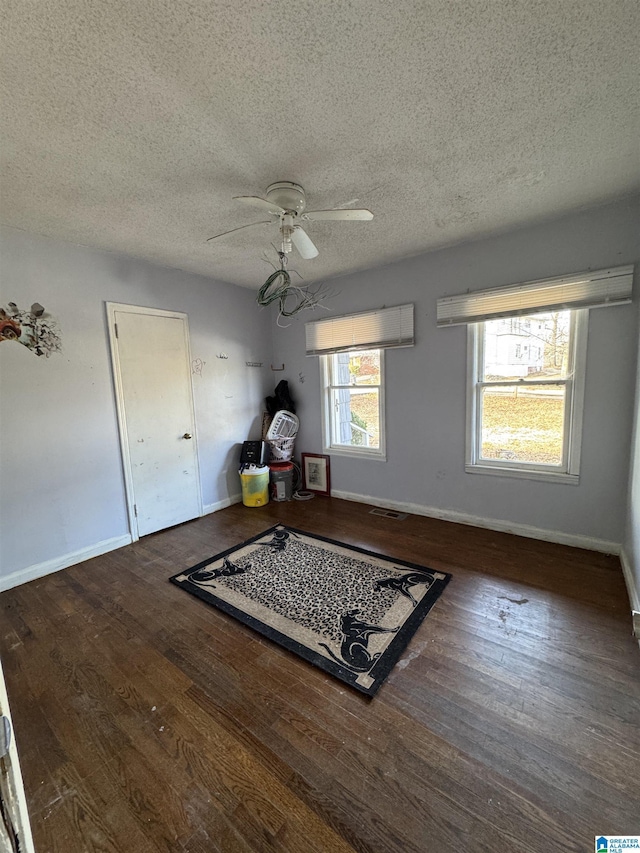 interior space featuring ceiling fan, dark wood-type flooring, and a textured ceiling