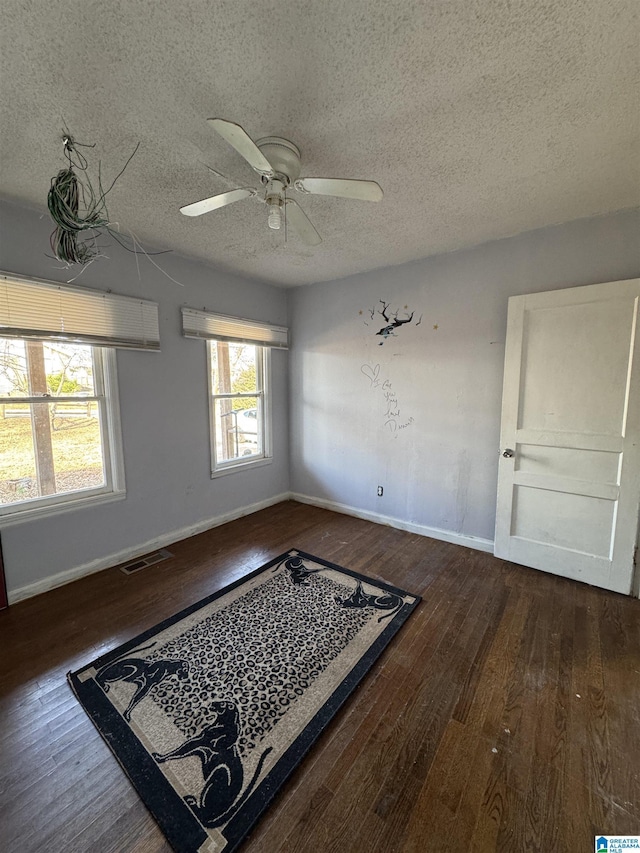 unfurnished room with ceiling fan, a textured ceiling, and dark hardwood / wood-style flooring