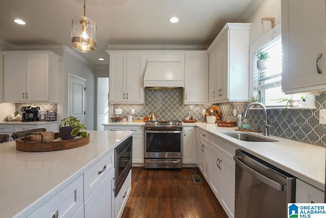 kitchen featuring sink, appliances with stainless steel finishes, white cabinetry, decorative light fixtures, and custom exhaust hood