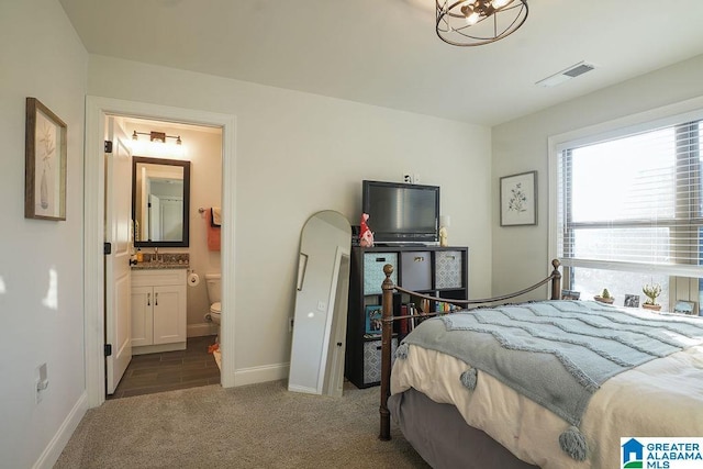 carpeted bedroom featuring ensuite bathroom and sink