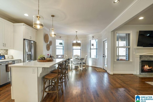 kitchen featuring pendant lighting, stainless steel appliances, a center island, white cabinets, and a kitchen bar