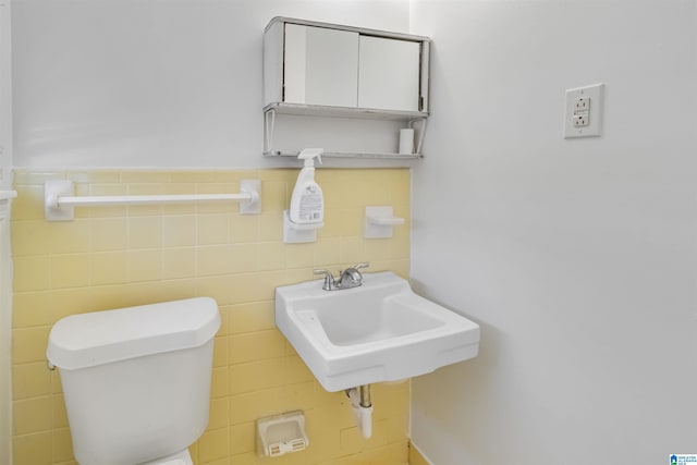 bathroom featuring sink, tile walls, and toilet