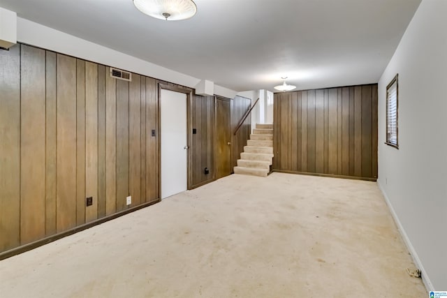 basement featuring light colored carpet and wooden walls