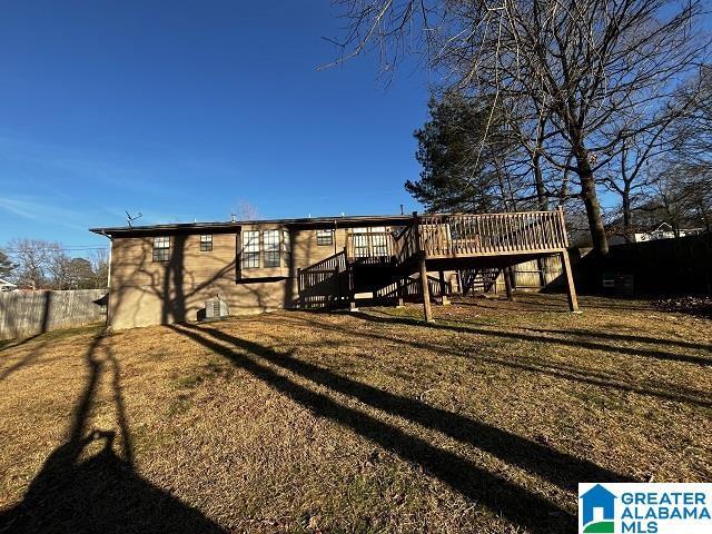 back of property with a deck and a lawn