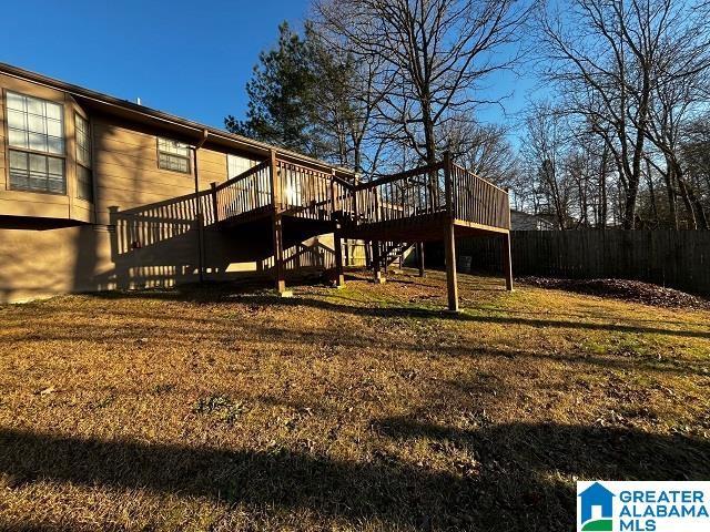 back of property featuring a wooden deck and a lawn