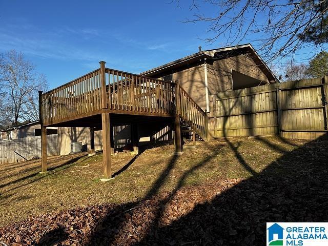 rear view of house featuring cooling unit, a wooden deck, and a yard