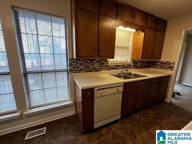 kitchen featuring sink, backsplash, a textured ceiling, and dishwasher