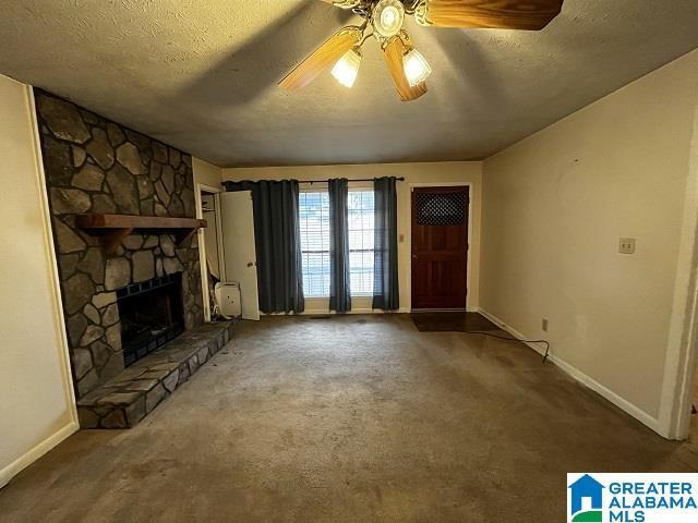 unfurnished living room with ceiling fan, carpet, a textured ceiling, and a fireplace