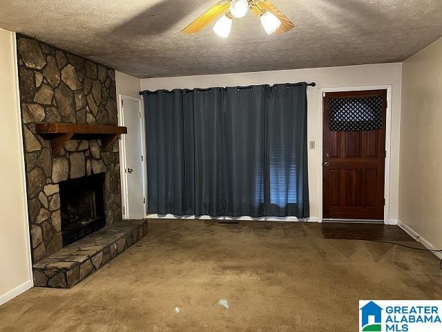 carpeted foyer featuring ceiling fan, a fireplace, and a textured ceiling