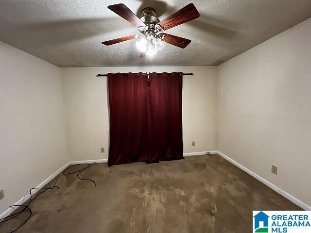 carpeted spare room featuring ceiling fan and a textured ceiling