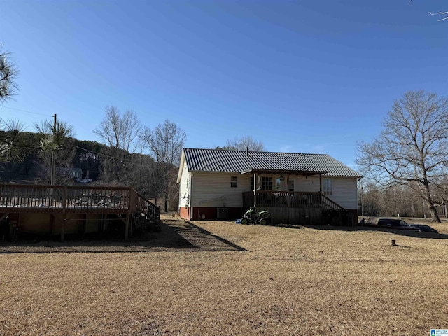 rear view of house featuring a wooden deck and a lawn