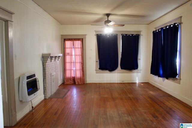 interior space with a ceiling fan, baseboards, heating unit, and hardwood / wood-style flooring