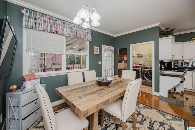 dining room featuring ornamental molding, light hardwood / wood-style floors, washer and dryer, and a notable chandelier