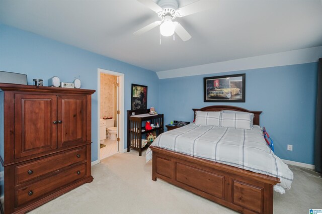 bedroom with ensuite bathroom, light colored carpet, and ceiling fan