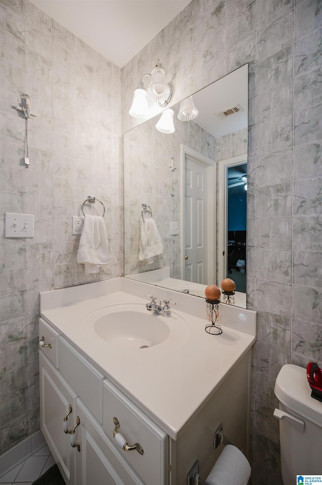 bathroom with tile patterned floors, vanity, toilet, and tile walls