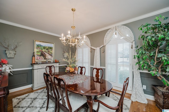 dining space featuring crown molding, light hardwood / wood-style floors, and a notable chandelier