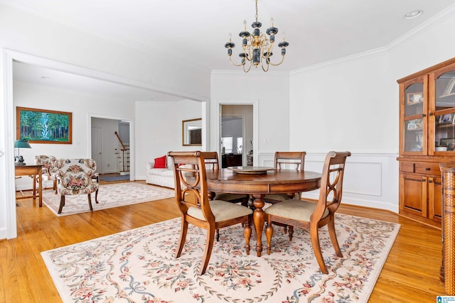 dining room with ornamental molding, a notable chandelier, and light hardwood / wood-style flooring