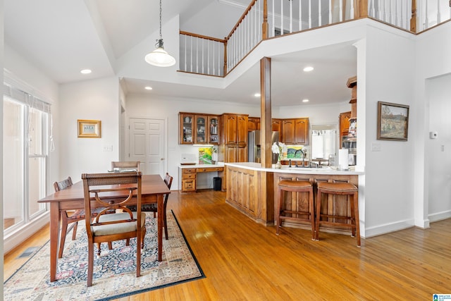 dining space with sink, crown molding, high vaulted ceiling, and light wood-type flooring