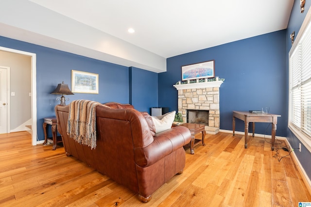 living room featuring a stone fireplace and light hardwood / wood-style floors