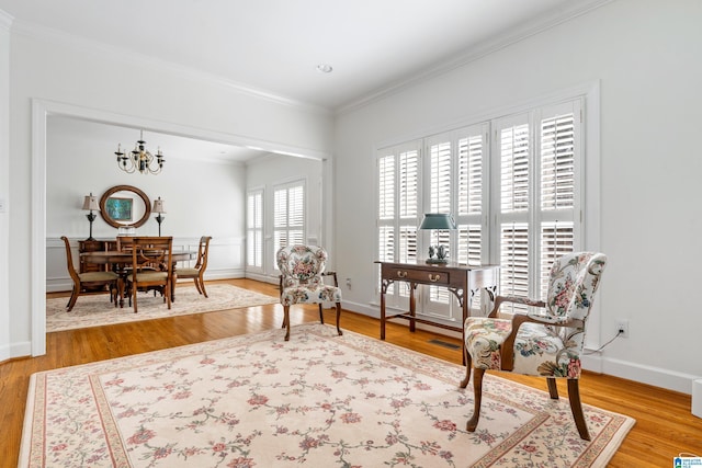 living area featuring crown molding, wood-type flooring, and an inviting chandelier