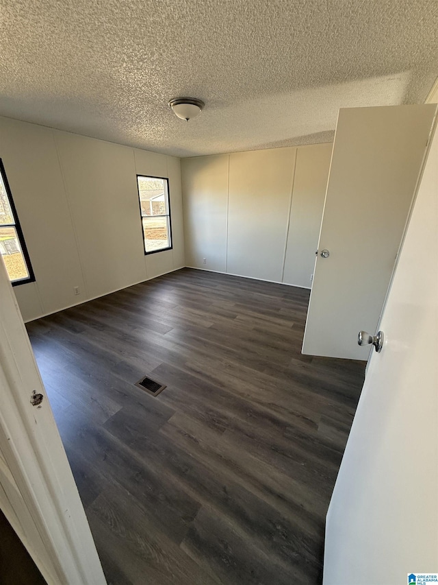 unfurnished bedroom featuring dark wood-type flooring and a textured ceiling