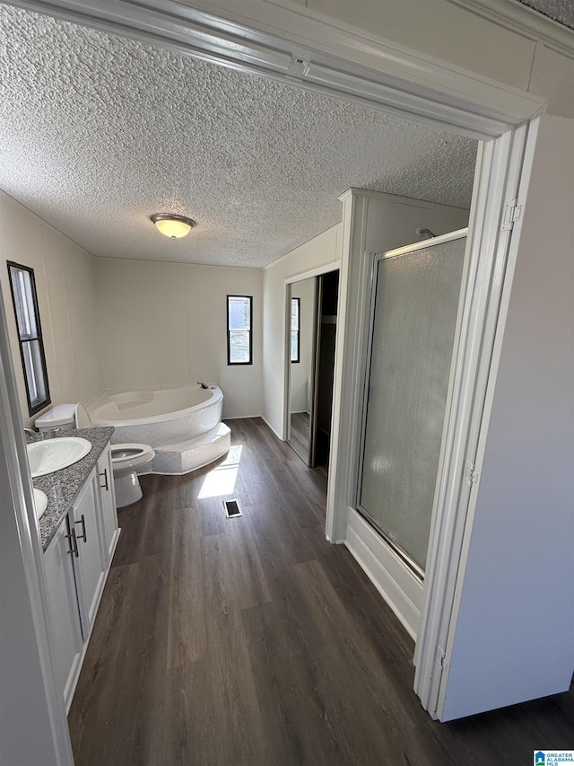 full bathroom with toilet, separate shower and tub, a textured ceiling, vanity, and hardwood / wood-style floors